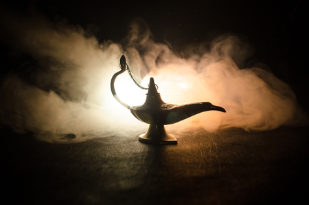 Antique Aladdin arabian nights genie style oil lamp with soft light white smoke, Dark background. Lamp of wishes conceptの写真素材