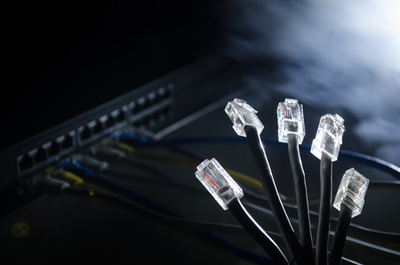 Network switch and ethernet cables, symbol of global communications. Colored network cables on dark background with lights and smoke. Selective focus. Network internet concept backgroundの写真素材