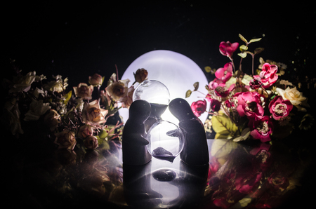 Two doll hugging on table with flowers and moon decoration Lighted background with smoke.Love concept. Greeting or gift card design idea. Silhouette of hugging coupleの写真素材