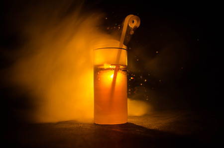bright yellow green cocktail garnished with lime. Classic alcohol cocktails, cocktails at the bar, alcoholic drinks, soft drinks, tasty cocktails on dark background with smoke and lightの写真素材