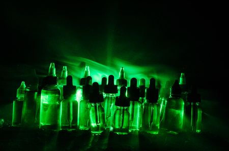 Vape concept. Smoke clouds and vape liquid bottles on dark background. Light effects. Useful as background or vape advertisement or vape background.の写真素材