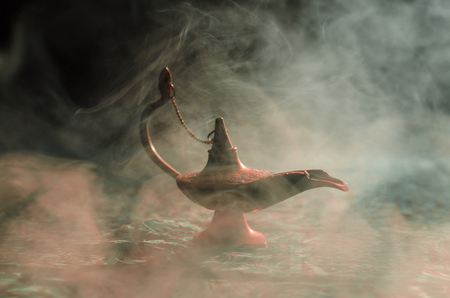 Antique Aladdin arabian nights genie style oil lamp with soft light white smoke, Dark background. Lamp of wishes conceptの写真素材