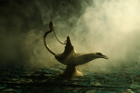 Antique Aladdin arabian nights genie style oil lamp with soft light white smoke, Dark background. Lamp of wishes conceptの写真素材