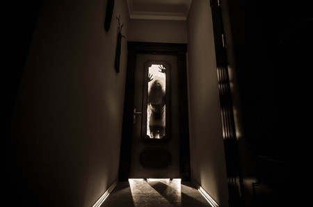 Silhouette of an unknown shadow figure with hands on a door through a closed glass door. Horror conceptの写真素材