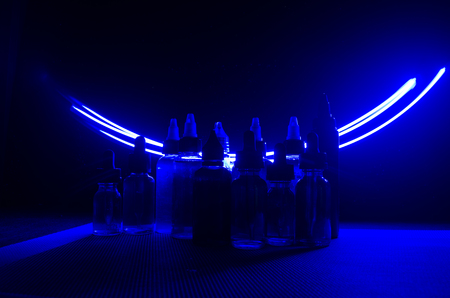Vape concept. Smoke clouds and vape liquid bottles on dark background. Light effects. Useful as background or vape advertisement or vape background.の写真素材