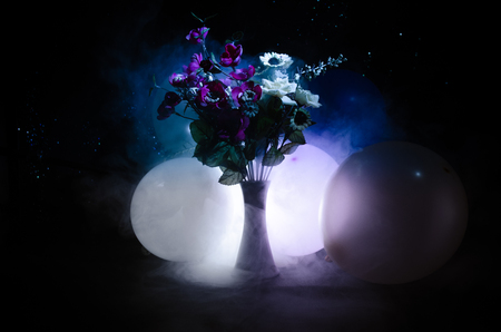 Picturesque purple spring flowers in glass vase standing in a row on a dark background with stars with light and fog. Flower concept with balloonの写真素材