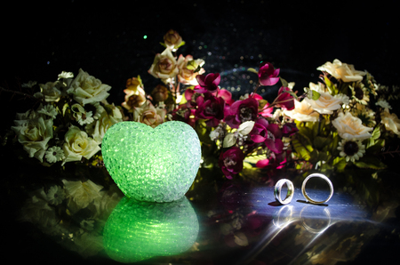 Wedding card, Wedding rings. Wedding bouquet, background. Flowering branch with white delicate flowers on wooden surface. Declaration of love, spring. Dark background with smoke and heart. Love coneptの写真素材