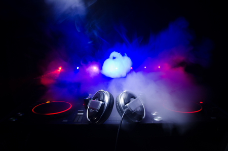 DJ Spinning, Mixing, and Scratching in a Night Club, Hands of dj tweak various track controls on dj's deck, strobe lights and fog, selective focus, close upの写真素材