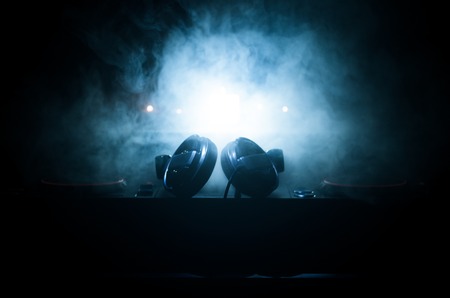 DJ Spinning, Mixing, and Scratching in a Night Club, Hands of dj tweak various track controls on dj's deck, strobe lights and fog, selective focus, close upの写真素材