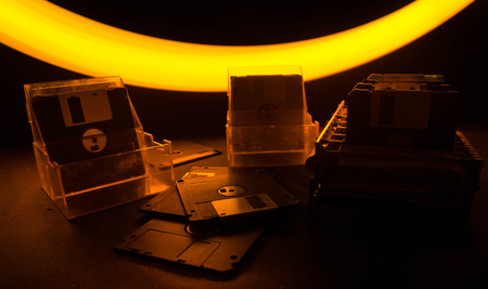 Pile of black floppy disks (diskette) on dark background with lightの写真素材