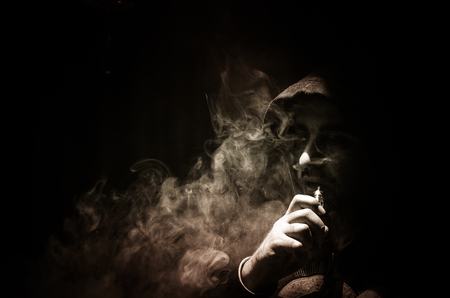 Vaping man holding a mod. A cloud of vapor. Black background. Vaping an electronic cigarette with a lot of smoke. Vape conceptの写真素材