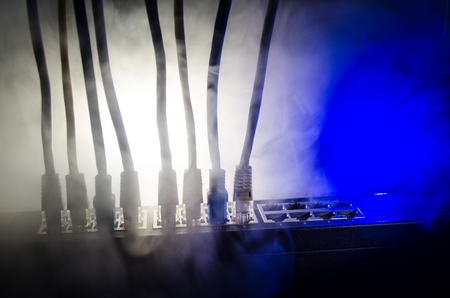 Network switch and ethernet cables, symbol of global communications. Colored network cables on dark background with lights and smoke. Selective focus. Network internet concept backgroundの写真素材