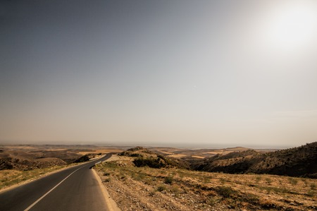Road vanishing to the horizon under sun rays coming down trough the dramatic stormy clouds. Sunset at the mountain road. Azerbaijan,の写真素材