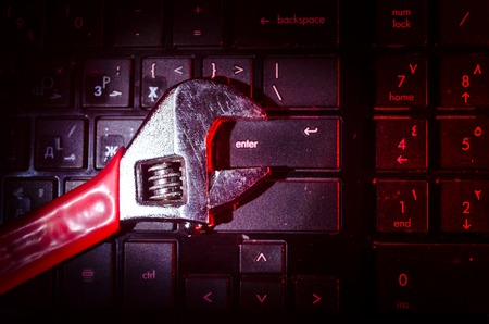 Wrench tool over a laptop on a dark background close up selective focus, repair service concept.の写真素材