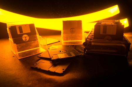 Pile of black floppy disks (diskette) on dark background with light