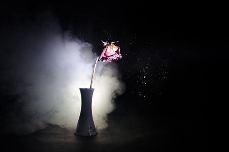 A wilting rose signifies lost love, divorce, or a bad relationship, dead rose on dark background with smokeの写真素材