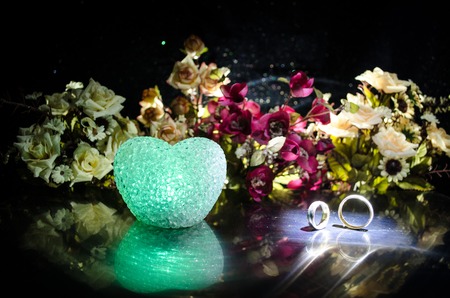 Wedding card, Wedding rings. Wedding bouquet, background. Flowering branch with white delicate flowers on wooden surface. Declaration of love, spring. Dark background with smoke and heart. Love coneptの写真素材