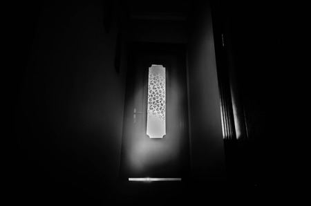 Silhouette of an unknown shadow figure with hands on a door through a closed glass door. Horror conceptの写真素材