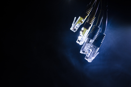 Network switch and ethernet cables, symbol of global communications. Colored network cables on dark background with lights and smoke. Selective focus. Network internet concept backgroundの写真素材