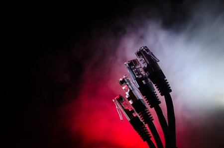 Network switch and ethernet cables, symbol of global communications. Colored network cables on dark background with lights and smoke. Selective focus. Network internet concept backgroundの写真素材
