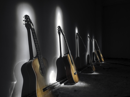 Acoustic guitar leaning on rusty wall in dark room with lights. Surreal view of a room with a guitars. Strobe light on guitarの写真素材