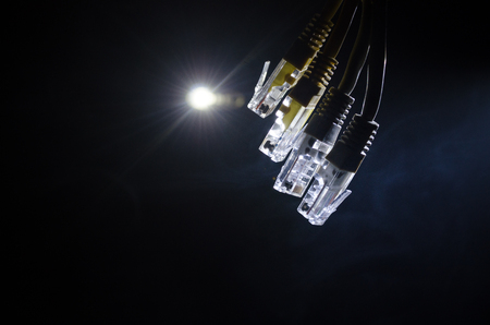 Network switch and ethernet cables, symbol of global communications. Colored network cables on dark background with lights and smoke. Selective focus. Network internet concept backgroundの写真素材