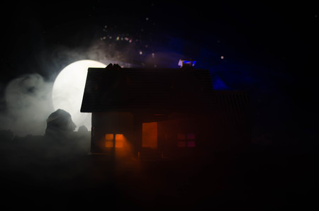 Old house with a Ghost in the moonlit night or Abandoned Haunted Horror House in fog. Old mystic villa with surreal big full moon. Horror Halloween concept.の写真素材