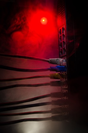 Network switch and ethernet cables, symbol of global communications. Colored network cables on dark background with lights and smoke. Selective focus. Network internet concept backgroundの写真素材