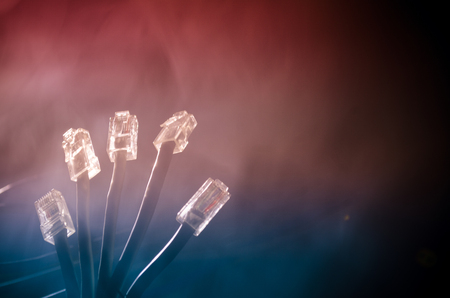Network switch and ethernet cables, symbol of global communications. Colored network cables on dark background with lights and smoke. Selective focus. Network internet concept backgroundの写真素材