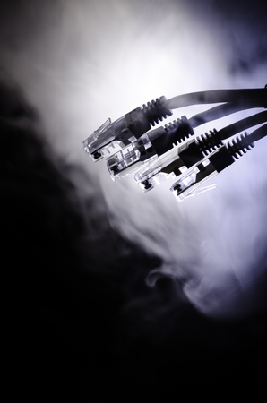 Network switch and ethernet cables, symbol of global communications. Colored network cables on dark background with lights and smoke. Selective focus. Network internet concept backgroundの写真素材