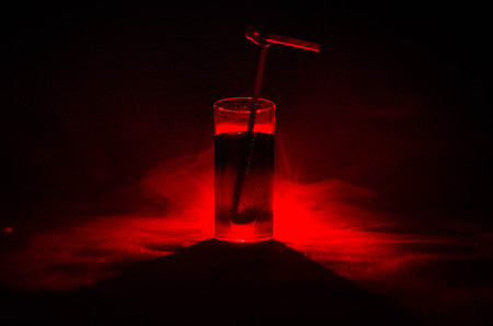 Glass of Red Alcoholic Cocktail on Dark Background with smoke and backlight. Fire hot coctailの写真素材