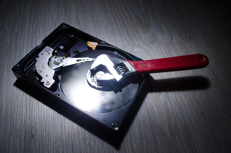 Adjustable wrench turn off a hard disk. On a dark background. Computer repair concept. Useful as background or posterの写真素材