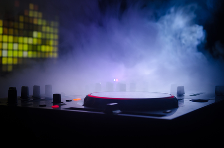 DJ Spinning, Mixing, and Scratching in a Night Club, Hands of dj tweak various track controls on dj's deck, strobe lights and fog, selective focus, close upの写真素材