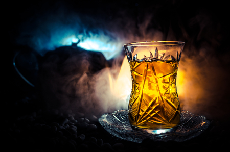 Turkish Azerbaijan tea in traditional glasse and pot on black background with lights and smoke. Eastern tea concept. Armudu traditional cupの写真素材