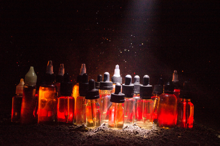 Vape concept. Smoke clouds and vape liquid bottles on dark background. Light effects. Useful as background or vape advertisement or vape background.の写真素材