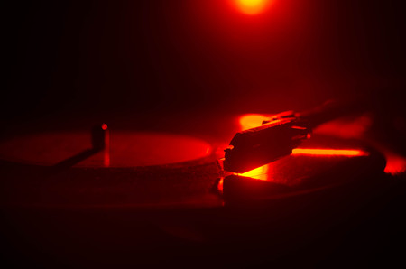 Turntable vinyl record player. Retro audio equipment for disc jockey. Sound technology for DJ to mix & play music. Vinyl record being played against burning fire background with smokeの写真素材