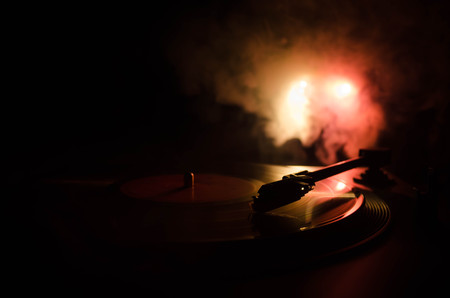 Turntable vinyl record player. Retro audio equipment for disc jockey. Sound technology for DJ to mix & play music. Vinyl record being played against burning fire background with smokeの写真素材