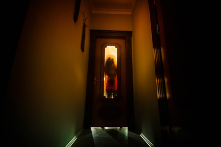 Silhouette of an unknown shadow figure with hands on a door through a closed glass door. Horror conceptの写真素材