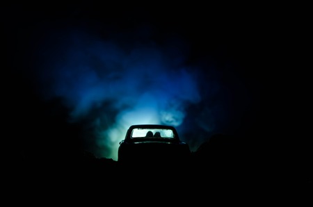 silhouette of car with couple inside on dark background with lights and smoke. Romantic sceneの写真素材