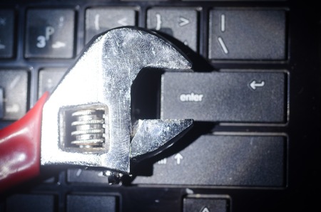 Wrench tool over a laptop on a dark background close up selective focus, repair service concept.の写真素材