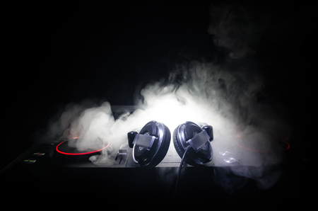 DJ Spinning, Mixing, and Scratching in a Night Club, Hands of dj tweak various track controls on dj's deck, strobe lights and fog, selective focus, close upの写真素材