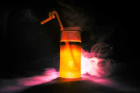 bright yellow green cocktail garnished with lime. Classic alcohol cocktails, cocktails at the bar, alcoholic drinks, soft drinks, tasty cocktails on dark background with smoke and lightの写真素材