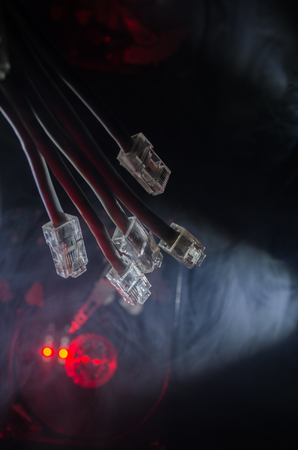 Network switch and ethernet cables, symbol of global communications. Colored network cables on dark...