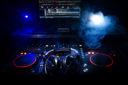 DJ Spinning, Mixing, and Scratching in a Night Club, Hands of dj tweak various track controls on dj's deck, strobe lights and fog, selective focus, close upの写真素材