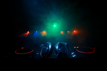 DJ Spinning, Mixing, and Scratching in a Night Club, Hands of dj tweak various track controls on dj's deck, strobe lights and fog, selective focus, close upの写真素材
