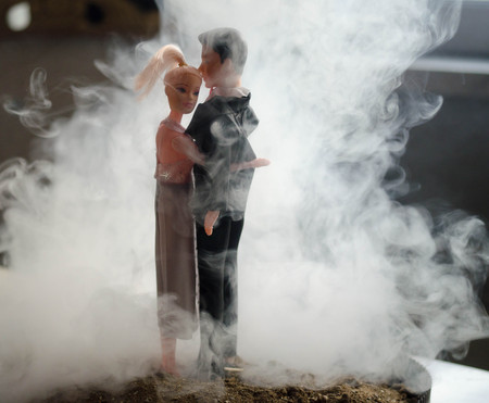 Doll wedding couple indoors is hugging each other. Beautiful model girl in white dress. Man in suit. Wedding love concept. Close up, smoke on background. Selective focusの写真素材