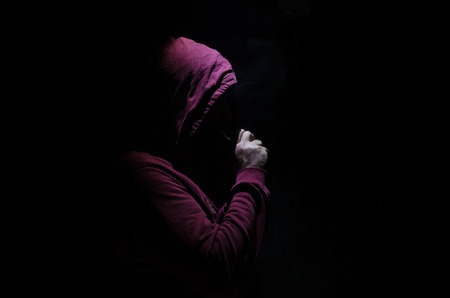 Vaping man holding a mod. A cloud of vapor. Black background. Vaping an electronic cigarette with a lot of smoke. Vape conceptの写真素材