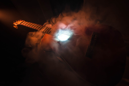Music concept. Acoustic guitar isolated on a dark background under beam of light with smoke with copy space. Guitar Strings, close up. Selective focus. Fire effects. Surreal guitarの写真素材