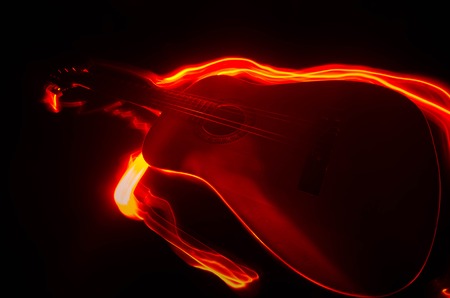Music concept. Acoustic guitar isolated on a dark background under beam of light with smoke with copy space. Guitar Strings, close up. Selective focus. Fire effects. Surreal guitarの写真素材