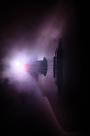 Music concept. Acoustic guitar isolated on a dark background under beam of light with smoke with copy space. Guitar Strings, close up. Selective focus. Fire effects. Surreal guitarの写真素材